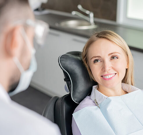 woman sitting in a dental chair, speaking with her dentist