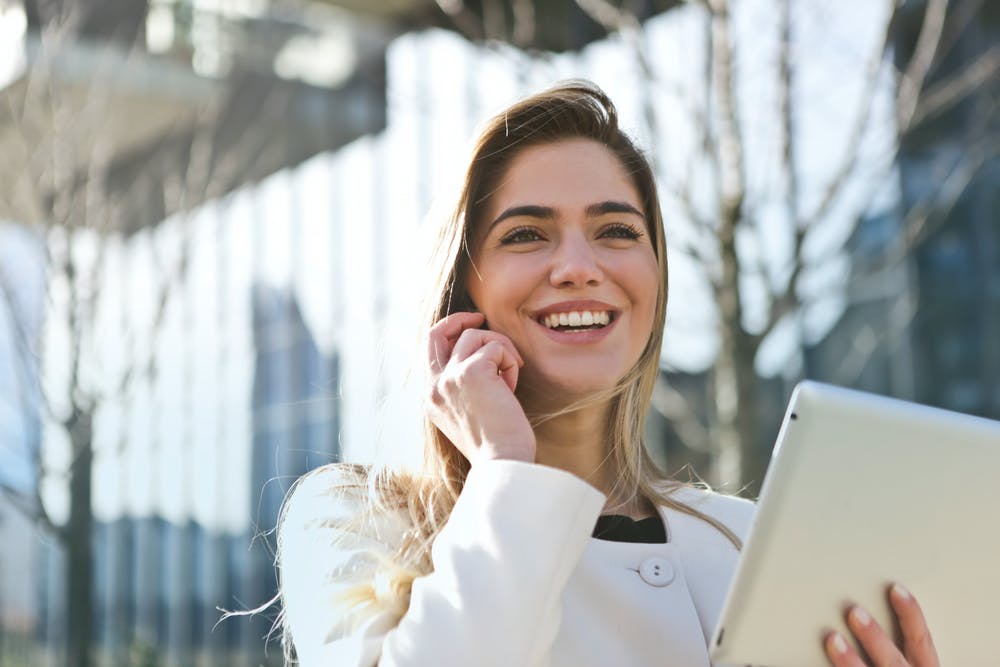 A young brunette woman walking on a windy day and looking at her iPad