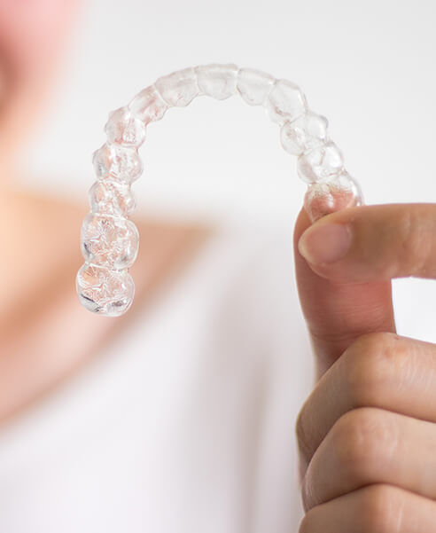 closeup of a person holding up a clear aligner