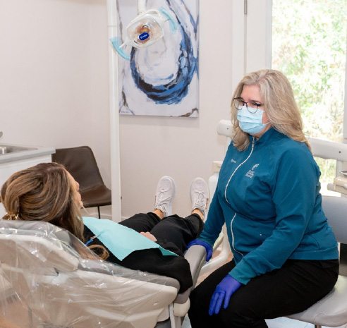 woman sitting in a dental chair, speaking with her dentist