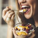 woman eating yogurt as part of a healthy diet for dental health and healthy teeth
