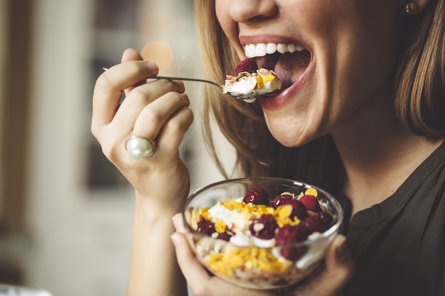 woman eating yogurt as part of a healthy diet for dental health and healthy teeth