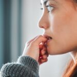 woman biting nails, a habit that hurts teeth