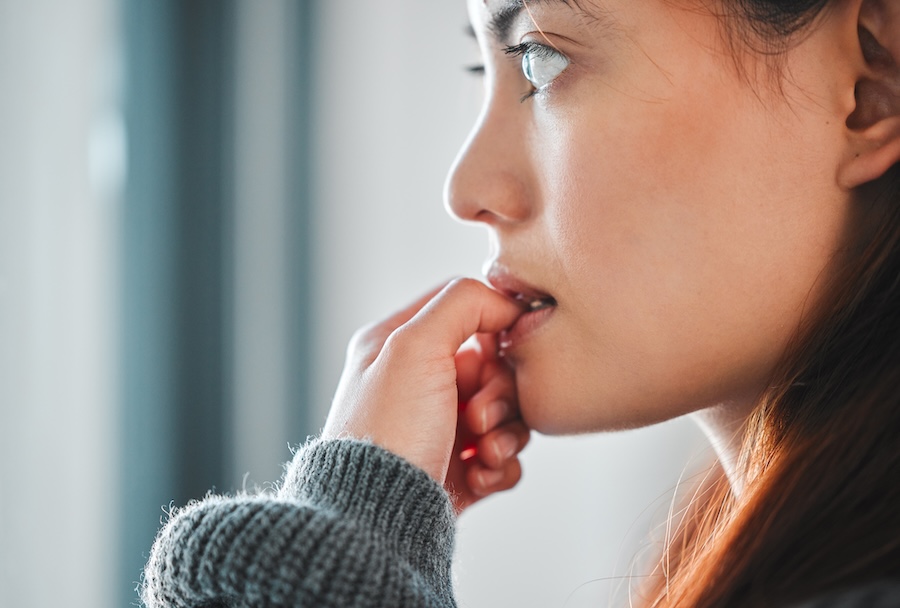 woman biting nails, a habit that hurts teeth