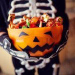 child holding bucket of halloween candy